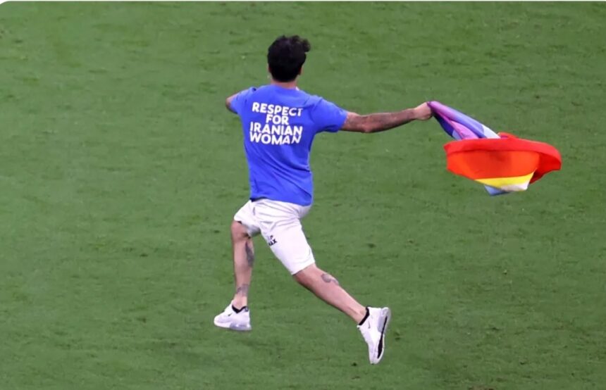 Un aficionado salta al campo con una bandera arcoíris en el Mundial de Qatar